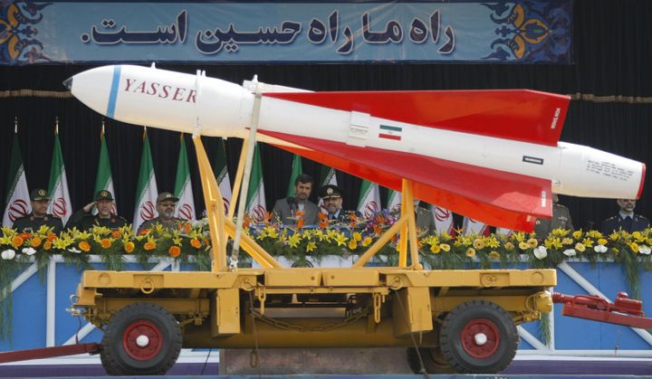 (FILES) Photo taken on April 18, 2009 of Iranian President Mahmoud Ahmadinejad (C-L) listening to airforce commander, Brigardier General Hassan Shah Safi (C-R), as a Yasser missile is paraded during Army Day celebrations in Tehran. The United States has downgraded the long-range missile threat posed by Iran based on intelligence reports, a Pentagon spokesman said on September 17, 2009. AFP PHOTO/BEHROUZ MEHRI (Photo credit should read BEHROUZ MEHRI/AFP/Getty Images)