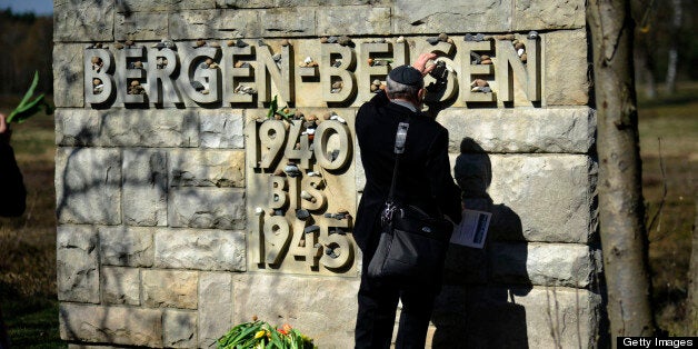 A man puts down a stone at the memorial site in Bergen-Belsen, northern Germany, during the ceremony to mark the 65th anniver