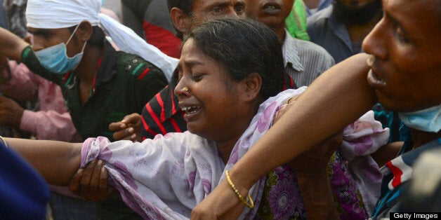 Bangladeshi relatives react after looking at the coffin of a victim following the collapse of an eight-storey building in Savar, on the outskirts of Dhaka on April 28, 2013. A fire broke out in the wreckage of a Bangladesh factory complex at night on April 28, killing the last known survivor from the building's collapse five days earlier, the national fire chief said. AFP PHOTO/Mnuir uz ZAMAN (Photo credit should read MUNIR UZ ZAMAN/AFP/Getty Images)