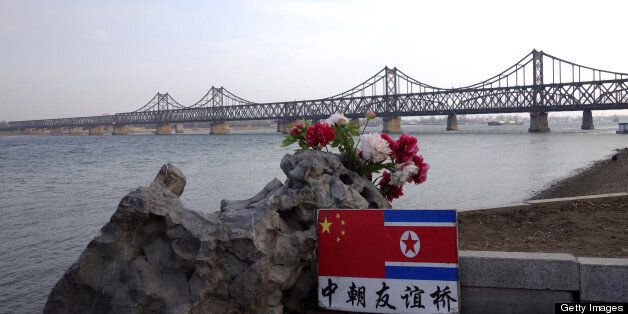 A sign displaying the Chinese (L) and North Korean (R) flags is pictured beside the Sino-Korean Friendship Bridge which leads to the North Korean town of Sinuiju, on the banks of the Yalu River, in Dandong, northeastern Liaoning province on April 10,2013. The biggest border crossing between North Korea and China has been closed to tourist groups, a Chinese official said as nuclear tensions mounted, but business travel was still allowed. AFP PHOTO/ WANG ZHAO (Photo credit should read WANG ZHAO/AFP/Getty Images)