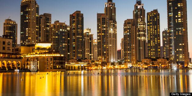 An image of a large group of newly-completed residential buildings in Dubai. These high-rises offer some outstanding views around the area. This was taken shortly after sunset, just as blue hour was creeping in, the golden/yellow lights create a shimmering gold reflections on the water. Taken on a warm day in January 2013.