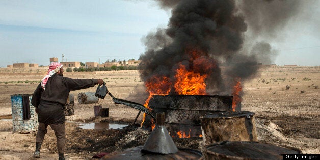 TO GO WITH AFP STORY BY JOSE MIGUEL CALATAYUD A picture taken on April 15, 2013 shows a Syrian man in the Al Raqqa countryside, who until three months ago was a farmer, pouring crude oil brought from Deir Ezzor province into a pit where it will be distilled as part of the refining process to produce fuel. Final products such as benzine and diesel are then sold to locals. Deir Ezzor contains the largest energy reserves in Syria, which produced some 420,000 of barrels of oil a day before the United States and the European Union banned the import of Syrian petroleum in 2011. AFP PHOTO/ALICE MARTINS (Photo credit should read ALICE Martins/AFP/Getty Images)