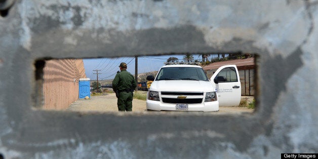 A US Border Patrol agent, seen through an opening in a fence, keeps watch on the 'border fence' near the San Ysidro port of entry along the US-Mexico border near San Diego, California on April 4, 2013. The barrier separating the two countries known to many as the 'border fence' or the 'border wall' is in reality several barriers, designed to prevent illegal movement across the border, backed by supporters and criticized by opponents. AFP PHOTO/Frederic J. BROWN (Photo credit should read FREDERIC J. BROWN/AFP/Getty Images)