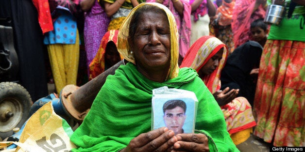 A Bangladeshi family member holds up the portrait of her missing relative as she offers prayers in front of the rubble of a n