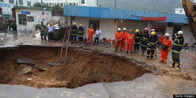 SHENZHEN, CHINA - MAY 21: (CHINA OUT) Rescuers search for people buried in a road cave-in accident site on May 21, 2013 in Shenzhen, China. Three people have been confirmed dead and two others injured after a road collapse engulfed five passers-by in Longgang district of Shenzhen city at around 9.00 pm local time Monday. (Photo by ChinaFotoPress/ChinaFotoPress via Getty Images)