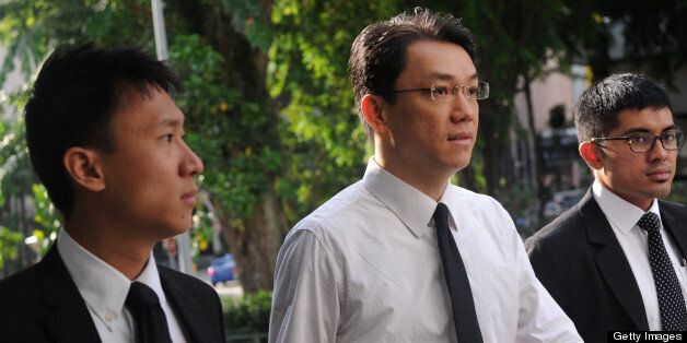 Former law professor Tey Tsun Hang (C in white shirt) arrives at the Subordinate Courts in Singapore on June 3, 2013. Tey was sentenced to five months in jail on June 3 by Chief District Judge Tan Siong Thye for obtaining sexual favours and gifts from a female student in exchange for good grades. AFP PHOTO/ROSLAN RAHMAN (Photo credit should read ROSLAN RAHMAN/AFP/Getty Images)