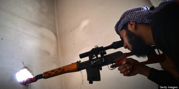 A Syrian rebel sniper observes the movement of Syrian government forces near Al-Kendi hospital in the northern Syrian city of