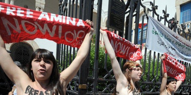 Three activists from the Femen feminist group, demonstrate in front of the justice Palace in Tunis, on May 29, 2013, before being arrested. The women, two French and the other German, shouted: 'Free Amina,' in reference to the young Tunisian woman imprisoned for protesting against hardline Islamists and awaiting trial for illegally possessing pepper spray. AFP PHOTO / FETHI BELAID (Photo credit should read FETHI BELAID/AFP/Getty Images)