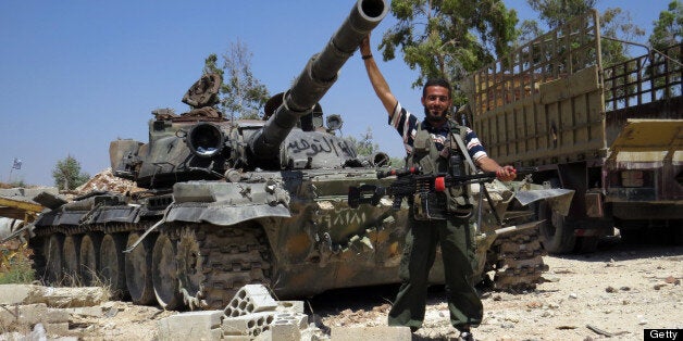 A Rebel fighter poses infront of a tank reportedly confiscated from an army barracks in the northwestern Syrian city of Sermin on June 14, 2013. The United States sharply toughened its line on Syria, promising rebels weapons for the first time, after saying it had evidence the regime had used chemical weapons, a charge Damascus dismissed as 'lies.' AFP PHOTO/MOHAMED KADDOUR (Photo credit should read MOHAMED KADDOUR/AFP/Getty Images)