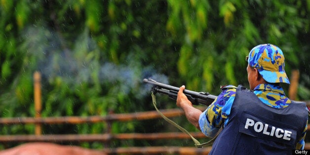 A Bangladeshi policeman fires a rubber bullet from a weapon while standing on a highway during clashes between garment workers and police in Asulia some 20kms north-west of Dhaka on July 31, 2010. Bangladeshi police fired rubber bullets in a bid to subdue garment workers who rioted for a second day in protest against low pay as unrest spread to areas outside Dhaka, police said. Workers fought pitched street battles with riot police in the manufacturing hub of Ashulia, north of Dhaka, as union officials rejected a government-backed pay hike as 'insultingly low.' AFP PHOTO/Munir uz ZAMAN (Photo credit should read MUNIR UZ ZAMAN/AFP/Getty Images)