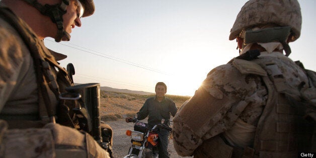 KAJAKI, AFGHANISTAN - OCTOBER 13: An Afghanistan National Policemen (ANP) reports to U.S. Marines 1st Lt. Ryan Cooper (L) of Lancaster, PA and an Afghan interpreter working with the Police Advisory team attached to India Battery, 3rd Battalion, 12th Marine Regiment that an Afghan civilian was severely injured by a blast from an improvised explosive device (IED) near Forward Operating Base (FOB) Zeebrugge on October 13, 2010 in Kajaki, Afghanistan. The Marines were on patrol when they heard the explosion, shortly after the report villagers brought the victim to them for help. (Photo by Scott Olson/Getty Images)