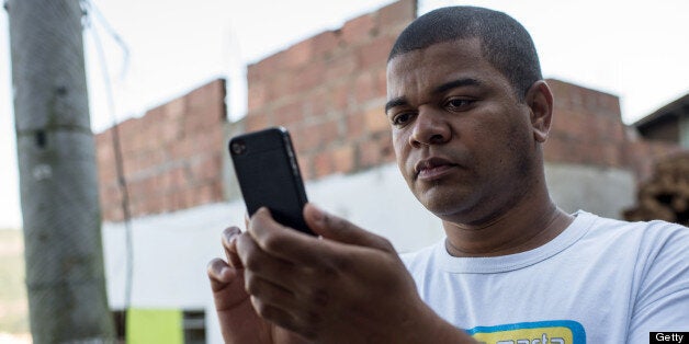 Favela tour guide Thiago Firmino takes a picture with his cell phone in Santa Marta shantytown in Rio de Janeiro, Brazil, on June 11, 2013. AFP PHOTO / YASUYOSHI CHIBA (Photo credit should read YASUYOSHI CHIBA/AFP/Getty Images)