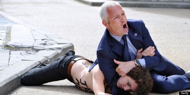 A security guard tackles to the ground a Femen activist as she tried along with two other feminist activists to stop the car of Tunisian Prime Minister from leaving the EU commission building after his working session with European Commission President on June 25, 2013 at the EU headquarters in Brussels. The European Commission urged Tunisia to reform criminal laws from its previous authoritarian regime as three topless feminist activists staged a protest by jumping on visiting Tunisian Prime Minister Ali Larayedh's car. Larayedh was visiting Brussels on the eve of an appeals hearing for three European activists from the feminist group Femen who were sentenced to four months in prison this month for baring their breasts in Tunis in a pro-Amina protest. AFP PHOTO GEORGES GOBET (Photo credit should read GEORGES GOBET/AFP/Getty Images)