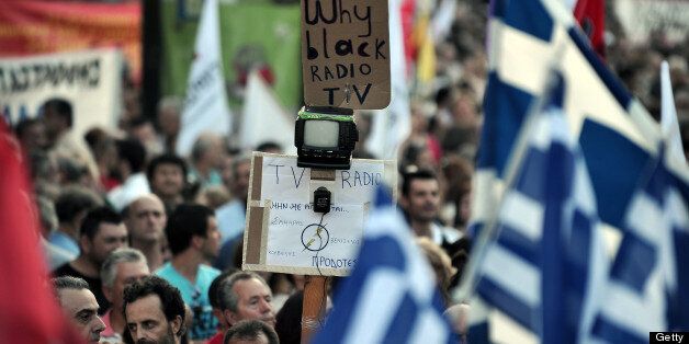 A protester holds a small TV unit and a plackard reading ' why black radio TV ' during a rally of the leftist Syriza party supporters on central Syntagma Square in Athens on June 17, 2013 to demand early elections .Prime Minister Antonis Samaras on Monday summoned an emergency meeting with his coalition allies as a furore over the shock shutdown of state broadcaster ERT threatened to bring down the government. AFP PHOTO/ LOUISA GOULIAMAKI (Photo credit should read LOUISA GOULIAMAKI/AFP/Getty Images)
