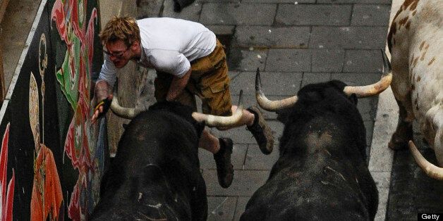 A participant is caught by one of the Victoriano del Rio bulls during the fourth bull run of the San Fermin Festival, in Pamplona, northern Spain on July 10, 2013. AFP PHOTO/ PEDRO ARMESTRE (Photo credit should read PEDRO ARMESTRE/AFP/Getty Images)