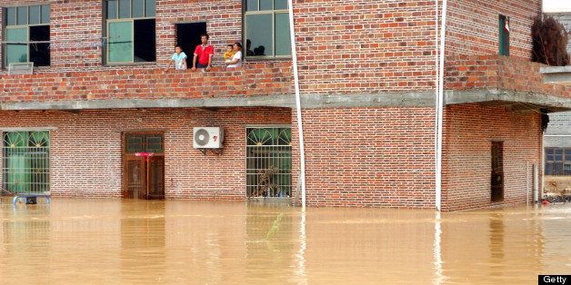 GANZHOU, CHINA - JULY 14: (CHINA OUT) A family looks out from the top floor of a flooded building as Typhoon Soulik hits on July 14, 2013 in Ganzhou, Jiangxi Province of China. Typhoon Soulik hit southern China on Saturday, causing flooding and a high risk of landslides. 300,000 people have been evacuated from the area, whilst 200 people have been left dead or missing. (Photo by ChinaFotoPress/ChinaFotoPress via Getty Images)