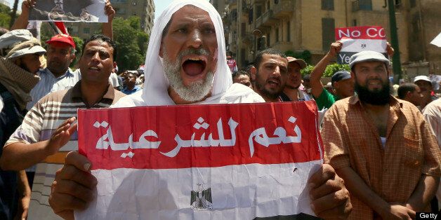 A supporter of the Muslim Brotherhood and Egypt's ousted president Mohamed Morsi, holds up a paper Egyptian flag with the words in Arabic, 'Yes to Legitimacy' as they demonstrate along a road leading to the government headquarter on July 17, 2013. Thousands of Mosri supporters marched on the streets of Cairo demanding the reinstatement of the toppled leader. AFP PHOTO/MARWAN NAAMANI (Photo credit should read MARWAN NAAMANI/AFP/Getty Images)