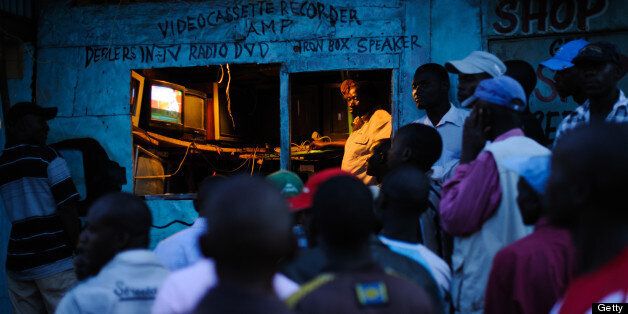 Men watch the incoming provisional election results on a television outside a shop in the Kibera slum of Nairobi, Kenya's capital, March 5, 2013. Kenya's deputy prime minister Uhuru Kenyatta, who faces an international crimes against humanity trial, took an initial lead in presidential elections today, the first since disputed polls five years ago sparked a wave of violence. AFP PHOTO/PHIL MOORE (Photo credit should read PHIL MOORE/AFP/Getty Images)