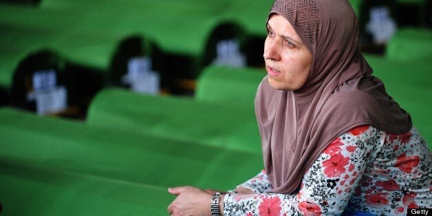 A Bosnian Muslim woman, survivor of Srebrenica 1995 massacre, mourns near body caskets of her relatives, layed out in a facto