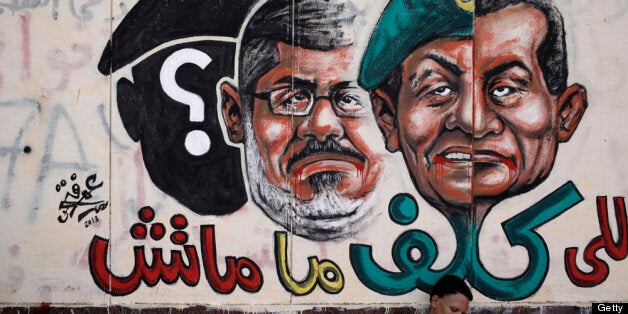 CAIRO, EGYPT - JULY 3: An opposition demonstrator sits below graffiti of Egyptian President Mohammed Morsi on the walls of Eg