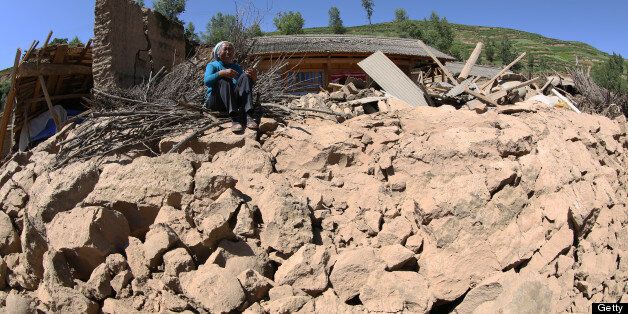 A resident cries on her collapsed house in Hetuo township in Dingxi, northwest China's Gansu province on July 22, 2013. Rescuers rushed to find victims buried by twin shallow earthquakes in northwest China Monday after the double tremors killed 73 people and injured almost 600, officials said. CHINA OUT AFP PHOTO (Photo credit should read STR/AFP/Getty Images)