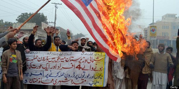 Pakistani demonstrators shout slogans beside a burning US flag during a protest in Multan on January 3, 2013, against the drone attacks in Pakistan's tribal areas. Pakistani warlord Mullah Nazir, who sent men to fight NATO troops in Afghanistan, was killed in a US drone strike in Pakistan along with five loyalists, local security officials said. He was the main militant commander in South Waziristan, part of Pakistan's northwestern tribal belt considered a base for Al-Qaeda, the Taliban and other Islamist militants, and a powerful elder in the Wazir tribe. AFP PHOTO/S.S MIRZA (Photo credit should read S.S MIRZA/AFP/Getty Images)