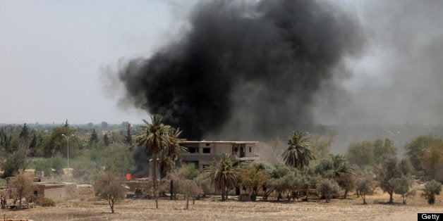 A picture taken on July 18, 2013 shows smoke rising from a building after opposition forces attacked a government forces held checkpoint in Syria's northeastern city of Deir Ezzor on July 18, 2013. More than 100,000 people have been killed in Syria since an uprising erupted against the rule of President Bashar al-Assad in March 2011, according to the Observatory's figures. AFP PHOTO / ABO SHUJA (Photo credit should read ABO SHUJA/AFP/Getty Images)