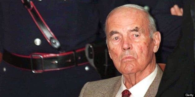 (FILES) This file picture taken on July 30, 1996 at a Rome military justice court shows former German SS officer Erich Priebke surrounded by carabinieri at a military court on Rome. Priebke, was found guilty of participating in the massacre of 335 civilians, including 75 Jews, at the Adreatine Caves outside Rome in March 1944 and sentenced to life imprisonment for his role in the massacre but later given house arrest due to his age. The Italian media said on April 1, 2011 that families of victims requested that Priebke case was examined again after he was seen doing his shopping or going to the restaurant in the Italian capital. AFP PHOTO / FILES / GERARD JULIEN (Photo credit should read GERARD JULIEN/AFP/Getty Images)