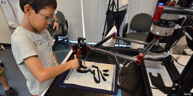 A boy writes a Chinese letter for 'study' with a calligraphy robot, which mimics the exact brush strokes of a master calligra