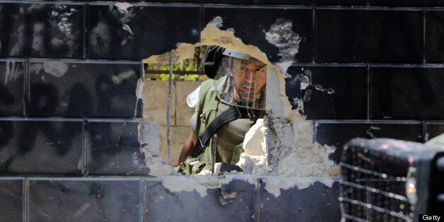An Israeli security guard peers at a hole knocked through part of a wall contected to Israel's controversial separation barrier by Palestinian youth in the Abu Dis neighrbood, bordering Jerusalem on July 9, 2013. Israel says the barrier is needed to prevent attacks but Palestinians, who refer to it as an 'Apartheid Wall,' say it cuts them off from occupied land that should be part of their future state. The International Court of Justice (ICJ) issued a non-binding resolution in 2004 calling for those parts of the barrier inside the West Bank to be torn down and for further construction in the territory to cease. Israel has ignored the ICJ ruling. AFP PHOTO/ABBAS MOMANI (Photo credit should read ABBAS MOMANI/AFP/Getty Images)