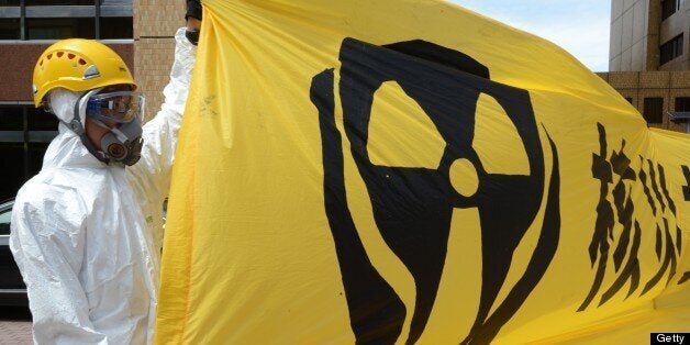 A masked Greenpeace demonstrator displays a banner in front of the state-run Taipower building to protest against the islands