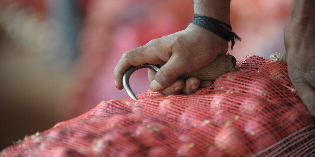 An Indian labourer prepares to carry onion bags towards waiting transport vehicles at a wholesale market yard in Hyderabad on