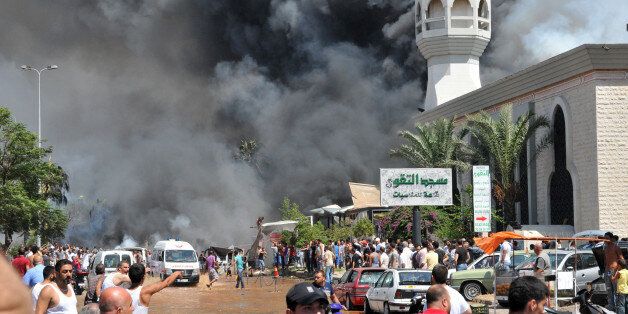 Smoke is seen above people gathering outside a mosque on the site of a powerful explosion in the northern Lebanese city of Tripoli on August 23, 2013. Two powerful explosions killed several people: one rocked the city centre near the home of outgoing Prime Minister Najib Mikati, the second one struck near the port of the restive city with a Sunni Muslim majority. The explosions come a week after a suicide car bombing killed 27 people in a Beirut stronghold of the Lebanese Shiite movement Hezbollah, which is fighting alongside Assad's forces. AFP PHOTO IBRAHIM CHALHOUB (Photo credit should read IBRAHIM CHALHOUB/AFP/Getty Images)