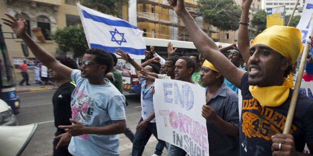 Eritreans, holding banners and the Israeli flags, shouts slogans as they walk from Levinsky Park to the US Embassy in the southern Mediterranean coastal city of Tel Aviv on June 29, 2012, to demonstrate against institutionalized racism and new deportation regulations introduced in Israel. Israeli Interior Minister Eli Yishai on June 28, gave illegal migrants from Ivory Coast 18 days to leave Israel voluntarily with a cash grant or be forcibly deported without aid. AFP PHOTO/JACK GUEZ (Photo credit should read JACK GUEZ/AFP/GettyImages)