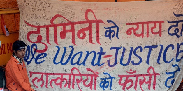 A protestor sits in front of a banner during a protest against last month's gang rape and murder of a student, in New Delhi on February 1, 2013. erdicts for five men accused of the fatal gang-rape of a student on a New Delhi bus would be handed down 'very soon,' a defence lawyer said , as an application to relocate the trial failed. AFP PHOTO/RAVEENDRAN (Photo credit should read RAVEENDRAN/AFP/Getty Images)