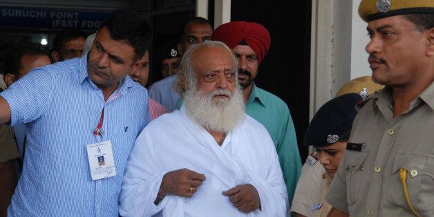 Indian spiritual guru Asaram Bapu (C) is escorted by police, after he was arrested from his Indore ashram, at the airport in Jodhpur on September 1, 2013. Police have arrested the popular Indian spiritual guru for an alleged sexual assault on a 16-year-old schoolgirl at a religious retreat in central India, a local official said. AFP PHOTO/ STR (Photo credit should read STRDEL/AFP/Getty Images)