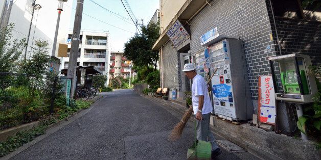 To go with Japan-Oly-2020-JPN,FOCUS by Shigemi SATO In this picture taken on September 14, 2013, 79-year-old resident Kohei Jinno sweeps and cleans a road before his apartment complex near the rebuilt national stadium in Tokyo. Tokyo's successful bid to host the Olympics made much of plans to re-use venues built for Japan's last Summer Games. But for Kohei Jinno, redevelopment for 2020 means eviction again, just like for 1964. In 1964, his home and business were torn down to make way for an Olympic park around the main stadium for the Tokyo Games. Now he has been told he must move again to make way for the stadium's redevelopment and expansion in time for 2020. AFP PHOTO / Yoshikazu TSUNO (Photo credit should read YOSHIKAZU TSUNO/AFP/Getty Images)