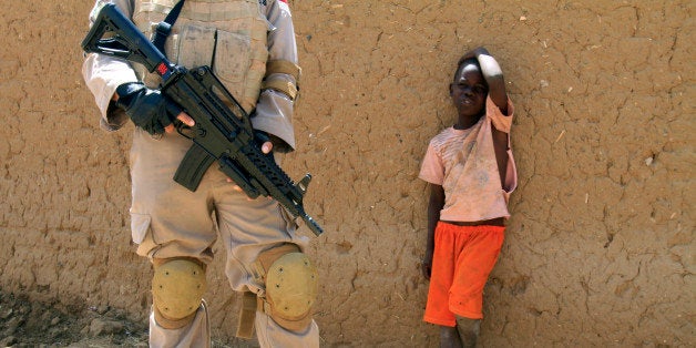 A young boy watches a United Nations peace keeper in the North Darfur state capital of El-Fasher, on June 17, 2013. The opening session of the two-day 'retreat' by Sudanese envoys, who meet every two years to review developments in Darfur, is taking place in El-Fasher in which Eltigani Seisi, head of the Darfur Regional Authority, told the meeting that traditional mediation techniques involving tribal elders are no longer effective. AFP PHOTO/ASHRAF SHAZLY (Photo credit should read ASHRAF SHAZLY/AFP/Getty Images)