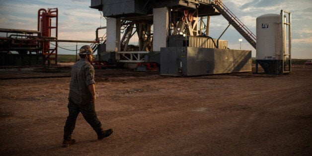 WATFORD CITY, ND - JULY 28: Leslie Lindeman, a motor man for Raven Drilling, works on an oil rig drilling into the Bakken shale formation on July 28, 2013 outside Watford City, North Dakota. North Dakota has been experiencing an oil boom in recent years, due in part to new drilling techniques including hydraulic fracturing and horizontal drilling. In April 2013, The United States Geological Survey released a new study estimating the Bakken formation and surrounding oil fields could yield up to 7.4 billion barrels of oil, doubling their estimate of 2008, which was stated at 3.65 billion barrels of oil. Workers for Raven Drilling work twelve hour days fourteen days straight, staying at a camp nearby, followed by fourteen days. (Photo by Andrew Burton/Getty Images)