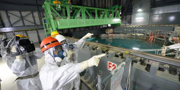 Fukushima Governor Yuhei sato (orange helmet) inspects the spent fuel pool in the unit 4 reactor building of Tokyo Electric P
