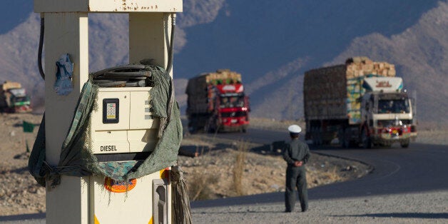 An Afghan policeman watches trucks driving on the highway 7, route between Pakistan and Afghanistan, next to a petrol station in Surobi province on January 22, 2011. AFP PHOTO/JOEL SAGET (Photo credit should read JOEL SAGET/AFP/Getty Images)