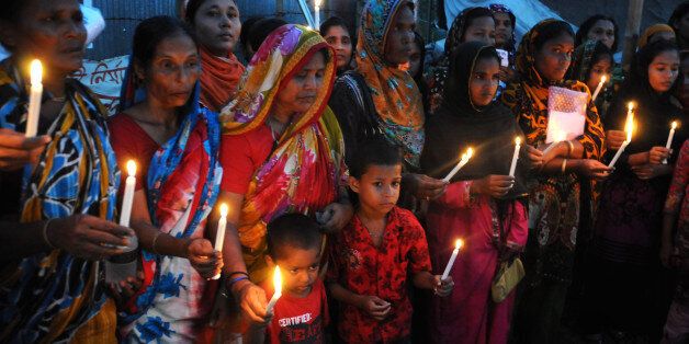 Bangladeshi garment workers and relatives of victims of the Rana Plaza building collapse hold candles during a memorial at the site of the Rana Plaza garment factory building collapse in Savar, on the outskirts of Dhaka on October 24, 2013, the six-month anniversary of the disaster. Relatives of the 1,135 people who lost their lives when the Rana Plaza complex collapsed on April 24 also said they had still to receive any compensation for their loss as they rallied at the site of the tragedy. AFP PHOTO/ SUVRA KANTI DAS (Photo credit should read SUVRA KANTI DAS/AFP/Getty Images)