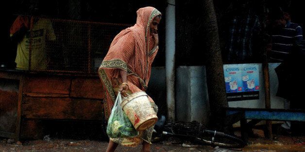 An elderly Indian woman carries daily essentials as she walk in a heavy cyclonic wind in Gopalpur, about 190 kilometers south of eastern city Bhubaneswar on October 12, 2013. Nearly half a million people have been evacuated from India's impoverished east coast ahead of a massive cyclone expected to make landfall on October 12 evening, disaster officials said. AFP PHOTO/ASIT KUMAR (Photo credit should read ASIT KUMAR/AFP/Getty Images)