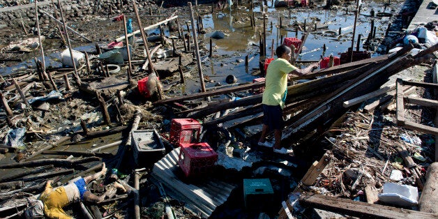 A victim lies among debris as a man (C) efforts to rebuild his house on stilts that had been swept away by the typhoon in a Tacloban neighbourhood almost completely flattened by the typhoon on November 18, 2013. Grieving survivors of a monster typhoon that smashed into the mainly Catholic Philippines flocked to shattered churches, as aid workers intensified efforts to reach desperate survivors in remote communities. AFP PHOTO / ODD ANDERSEN (Photo credit should read ODD ANDERSEN/AFP/Getty Images)