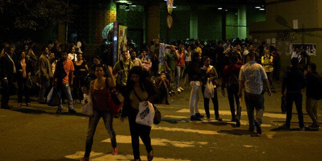 People stand outside a subway station during a general blackout in Caracas on December 2, 2013. AFP PHOTO/JUAN BARRETO