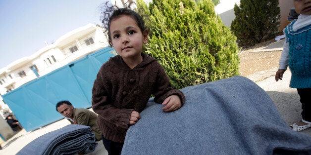 TO GO WITH AFP STORY BY SARA HUSSEIN
Syrian refugees receive thermal blankets and other humanitarian aid distributed by the