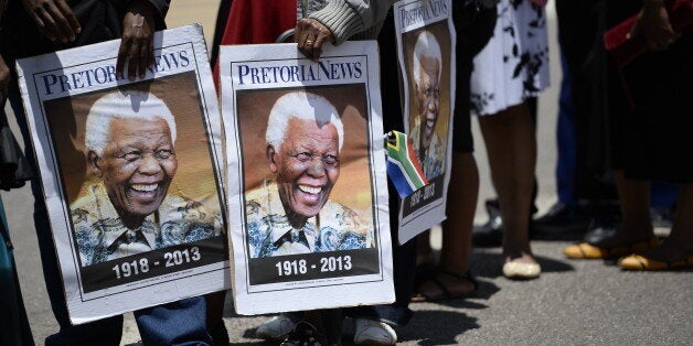 People hold portraits of Nelson Mandela as South Africans stand in line to pay their respect to South African former presiden