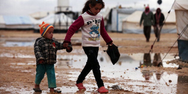 ZAATARI, JORDAN - DECEMBER 12: Syrian refugee children suffering from the heavy weather conditions walk on the mudy field around the tents in the Zaatari camp for Syrian refugees in north- east Jordan, December 12, 2013. (Photo by Salah Malkawi/Anadolu Agency/Getty Images)