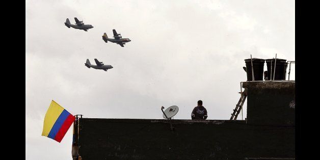 A man on a rooftop watches Colombian air force planes flying during Independence Day celebrations in Bogota, on July 20, 2012. AFP PHOTO/Luis Acosta (Photo credit should read LUIS ACOSTA/AFP/Getty Images)