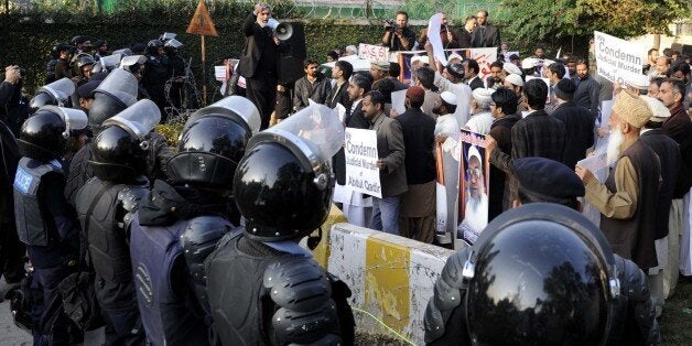 ISLAMABAD, PAKISTAN - DECEMBER 20: Pakistani policemen stand guard as members of Jamaat-e-Islami Pakistan stage a protest outside the Bangladesh high commission to condemn the execution of Bangladesh Jamaat-e-Islami Assistant Secretary Abdul Quader Mollah on December 20, 2013 in Islamabad, Pakistan. Mollah, 65, was executed on 12 December 2013 at Dhaka Central Jail in Bangladesh. (Photo by Metin Aktas/Anadolu Agency/Getty Images)